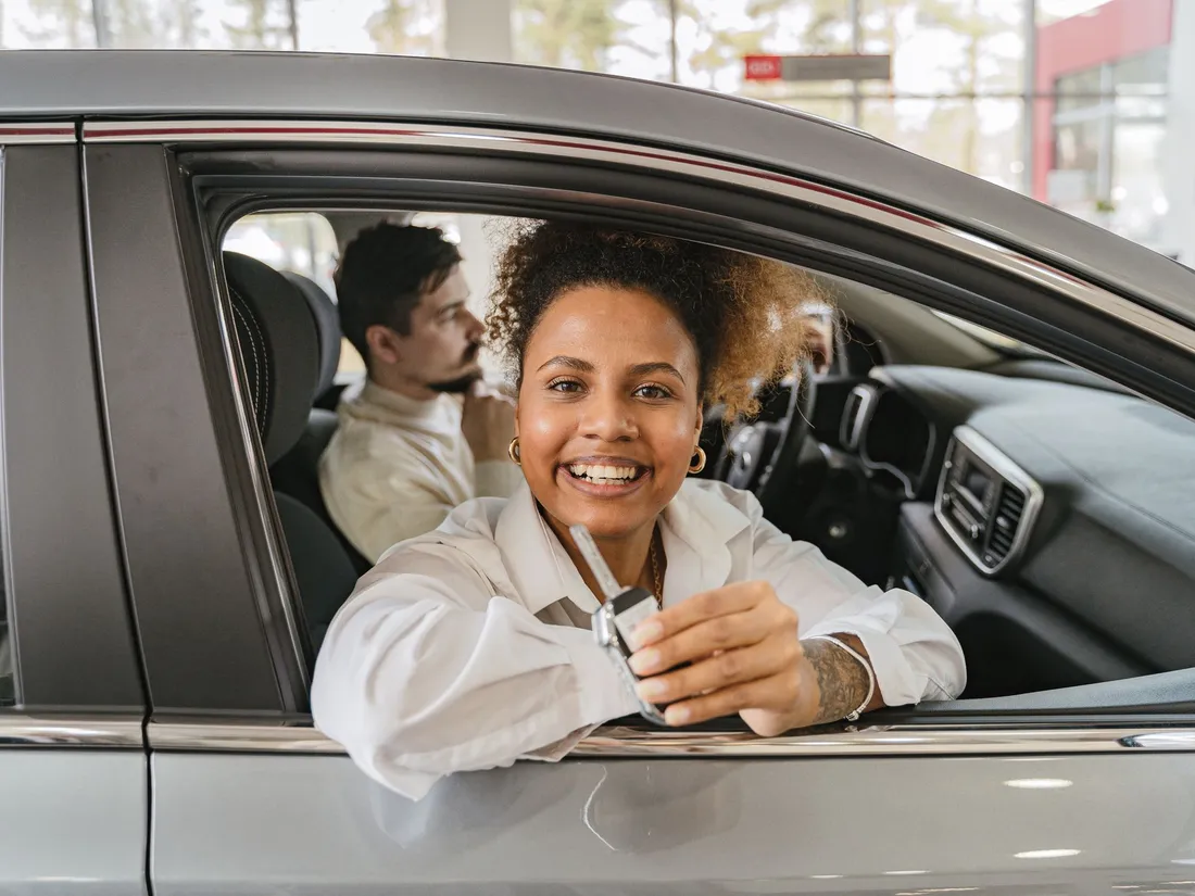 A smiling customer sitting in her new car, holding the keys